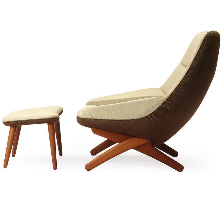 A beautifully proportioned, sculptural upholstered lounge chair having graceful crossed legs and an accompanying angled ottoman with turned-dowel legs.