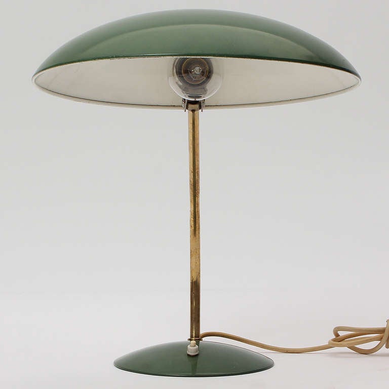 Une élégante lampe de bureau réglable avec une base en forme de disque émaillé vert émeraude et un abat-jour pivotant reliés par une tige en laiton incurvée:: par le designer formé au Bauhaus Christian Dell.