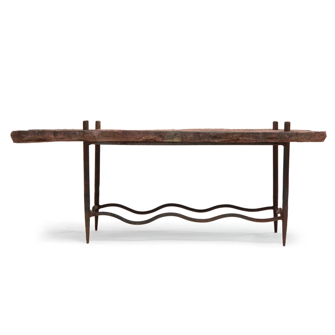 An American craftsman low / coffee table having a rough hewn, free-edged pierced stone top floating on a black handwrought iron base with undulating stretchers. Made in USA, circa 1960s.