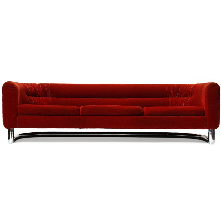 A three seat sofa in the original red velvet upholstery which floats on a tubular chromed steel bar base.