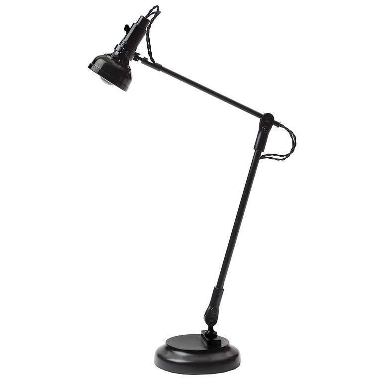 A masterfully fabricated adjustable patinated steel desk lamp having twin independently swiveling projector heads with a stem on two points of pivot rising from a stepped steel base.
