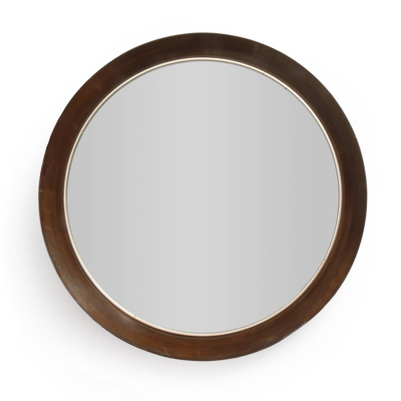 A finely crafted and substantial round wall mirror having a rich walnut frame with a sharply angled edge encasing a thick beveled mirror.