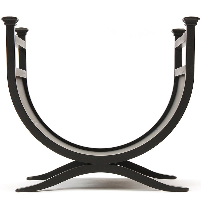 A U shaped blackened steel log holder with capital finials.