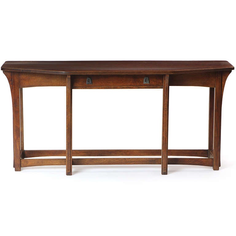 An elegant, finely crafted and unusual Arts and Crafts six-legged console table in quarter-sawn oak having a bowed front, expressive arched lower stretchers and hand-forged medallion ring pulls.