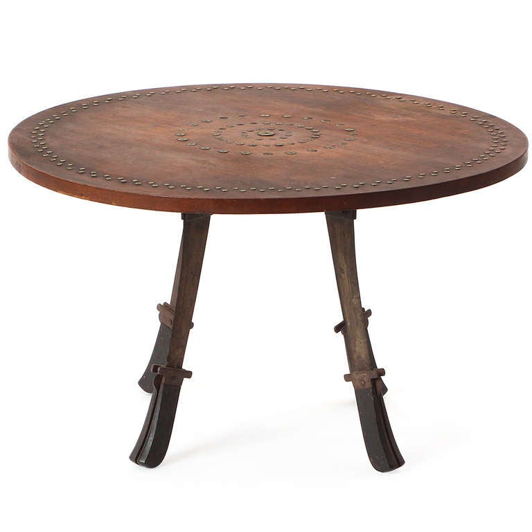 A unique handmade low table having legs made from antique folding machetes and an expressive top decorated with concentric patterns of inlaid vintage brass colt and Winchester shell casings.