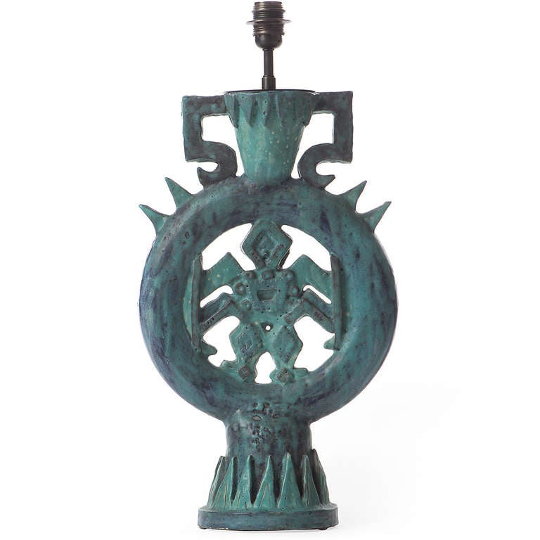 A dramatic, expressive pierced ceramic lamp having a symmetrical Aztec-influenced imagery and covered in a rich variegated blue-to-grey-to-green glaze (without shade). The base is hand-marked with a vessel, a sun, 'Callis' and 'Vallauris' in a brown