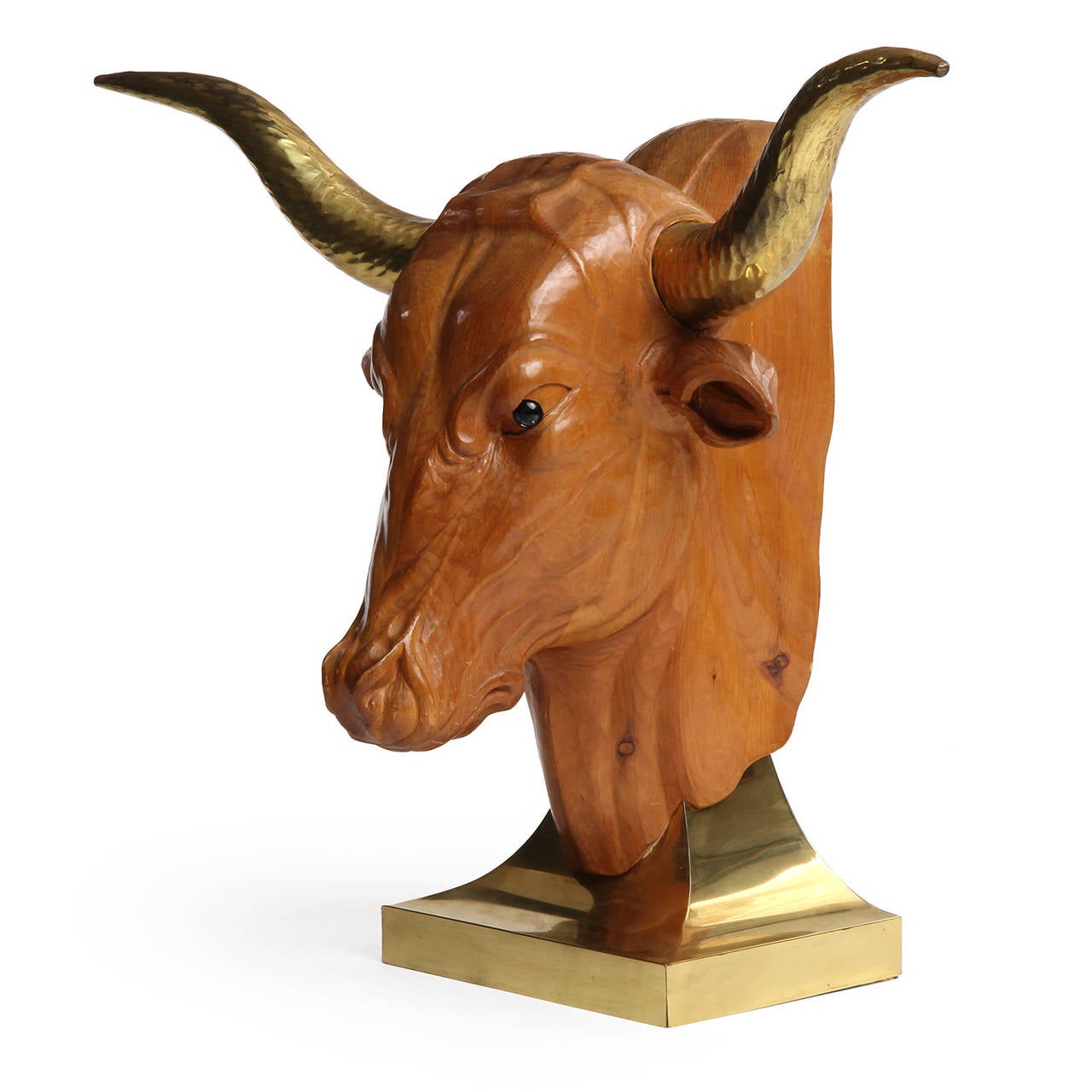 A carved, detailed, life sized wood sculpture of a bull's head with inset brass horns, mounted on a sloping lacquered brass base. Made in USA, circa 1960s.