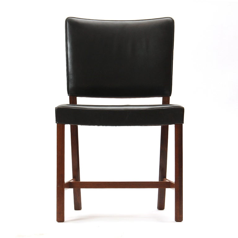 A rosewood dining chair with oiled black leather upholstery.