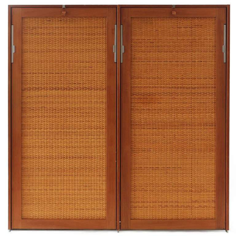A beautifully engineered wall-mounted cane-fronted cabinet of narrow depth that holds two individual drop-down single murphy beds. Designed by Hans J. Wegner and produced by Ry Mobler.
