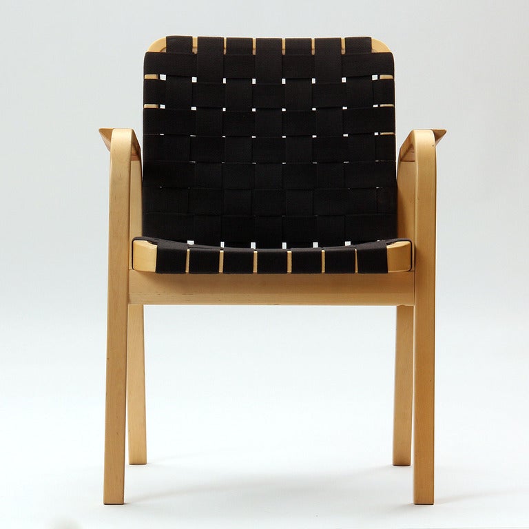 A laminated birch armchair with a black linen webbed seat and cane wrapped arms.