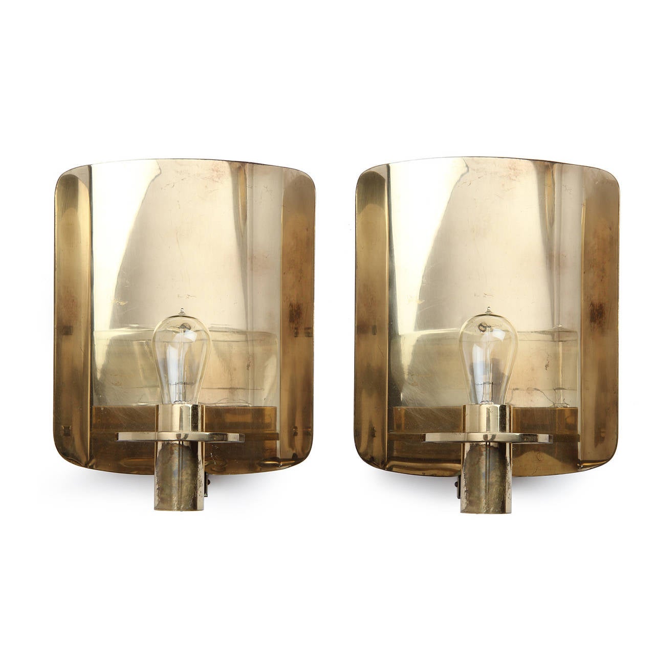 An elegant and uncommon pair of sconces in lacquered brass having a semicircular reflecting back panels and projecting sockets with Edison bulbs.