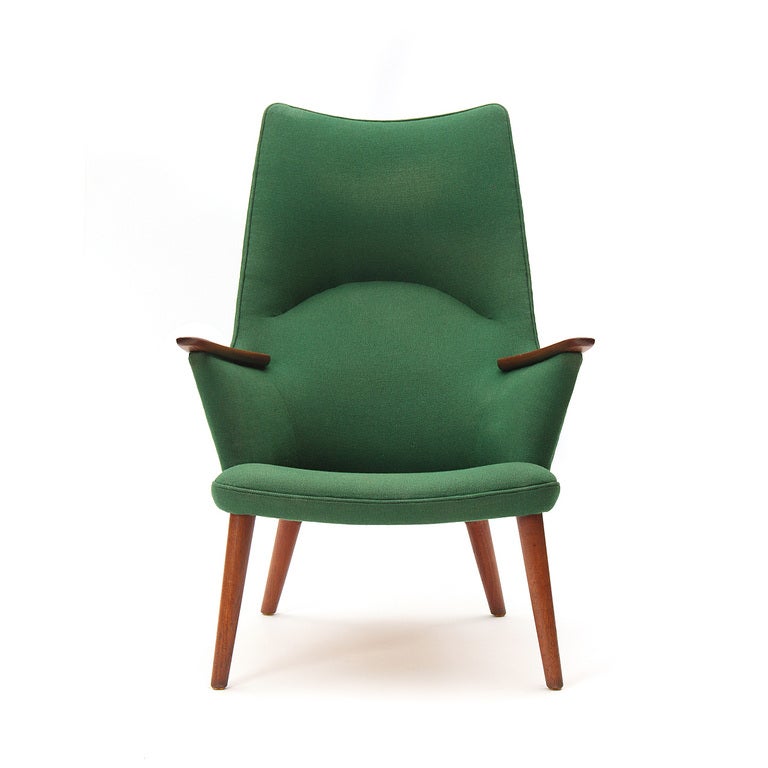 A high back lounge chair with teak arms and legs, retaining the original green wool upholstery.
