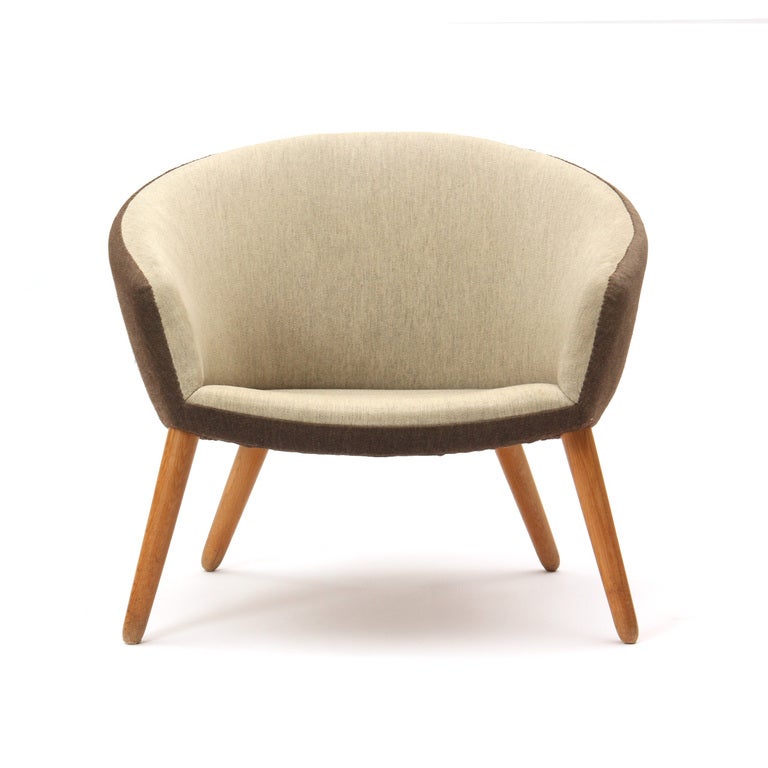 An upholstered barrel-back chairs upholstered in brown and tan wool fabric with oak legs. Designed by Nanna Ditzel and made by A.P. Stolen.