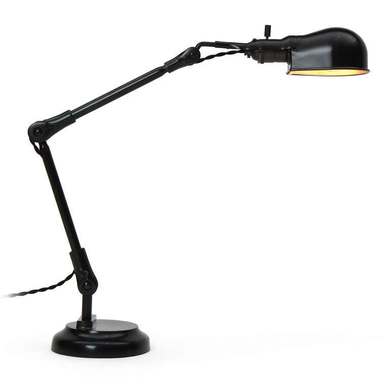 Une lampe de bureau réglable en acier patiné, avec un abat-jour pivotant en forme d'œuf fixé à une tige mince qui s'élève d'une base lestée et étagée.