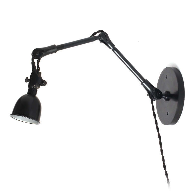 A patinated and polished steel articulating wall lamp having a slender stem supporting a pivoting shade emanating from a circular wall plate.