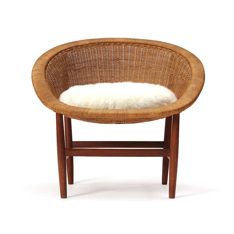 A teak frame supports a woven shell wicker seat. Made by L. Pontopiddan.