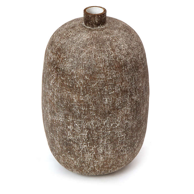 A large stoneware vase, its surface abraded and incised by vertical banding and partially covered in a white slip glaze. This piece is one of the largest ever made by the Cleveland ceramicist Claude Conover.