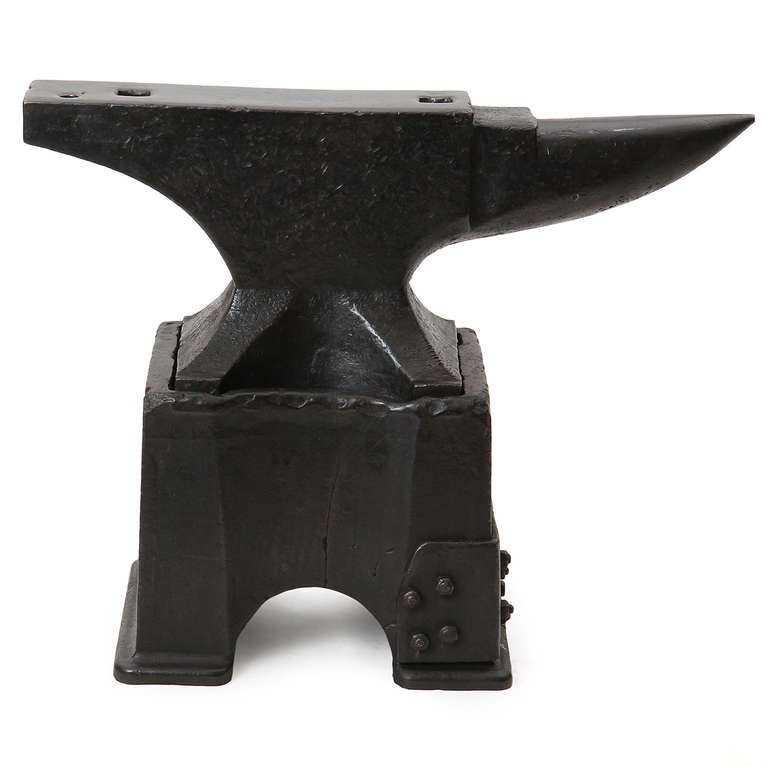 A wonderful and large-scaled anvil that rests on an uncommon separate cast iron arched base, both iron elements having a warm dark patina.