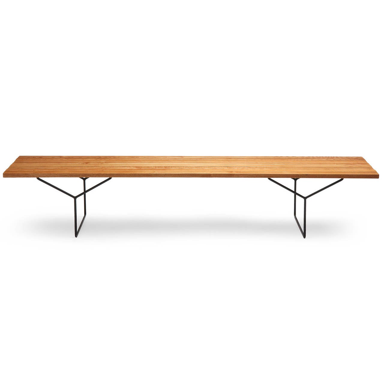 A bench or low table having an architectural blackened iron base with Y-shaped legs supporting a floating top of honey-toned parallel slats of figured white oak.