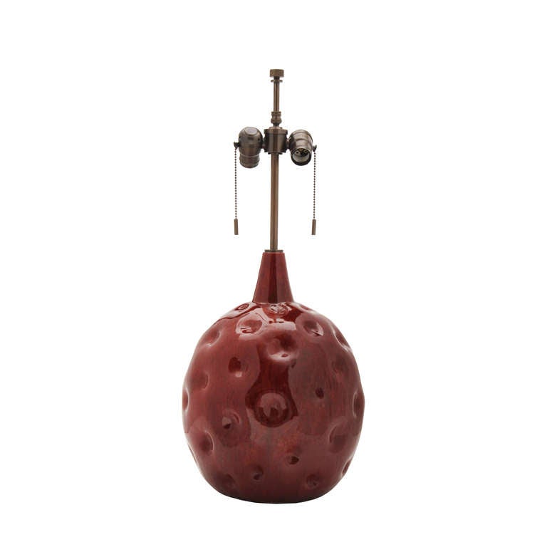 Substantial studio ceramic table lamp. Dimpled bulbous form with thick, mottled flambe raspberry glaze. Measure: Base is 15