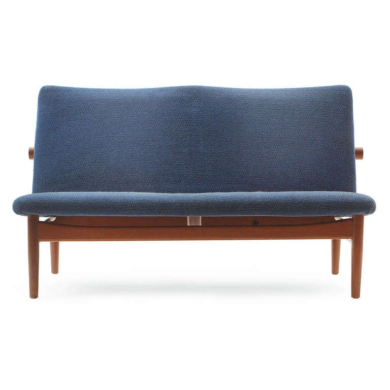 A sculptural and elegant armless 'Japan' settee designed by Finn Juhl. The settee / bench featuring an open architectural teak frame design with a distinctive back dowel support, and floating upholstered seat. Manufactured by France & Son in
