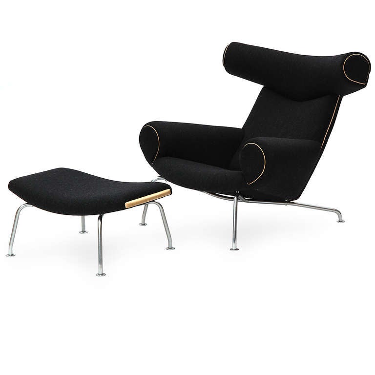 A pair of comfortable and stately Ox lounge chairs having generous head rests  and seats; upholstered in a rich charcoal Savak wool with leather welting and perched atop chromed steel tubular legs. 
The Ox chair was born from Wegner's fascination