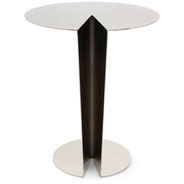 A dramatic and meticulously rendered polished stainless steel occasional table having cantilevered top rising from disc base, connected by tapering V-shaped base.