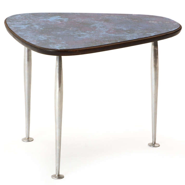 An unusual modernist side table having a rounded-wedge top surfaced with amethyst-hued Micarta floating on three footed aluminum dowel legs.
