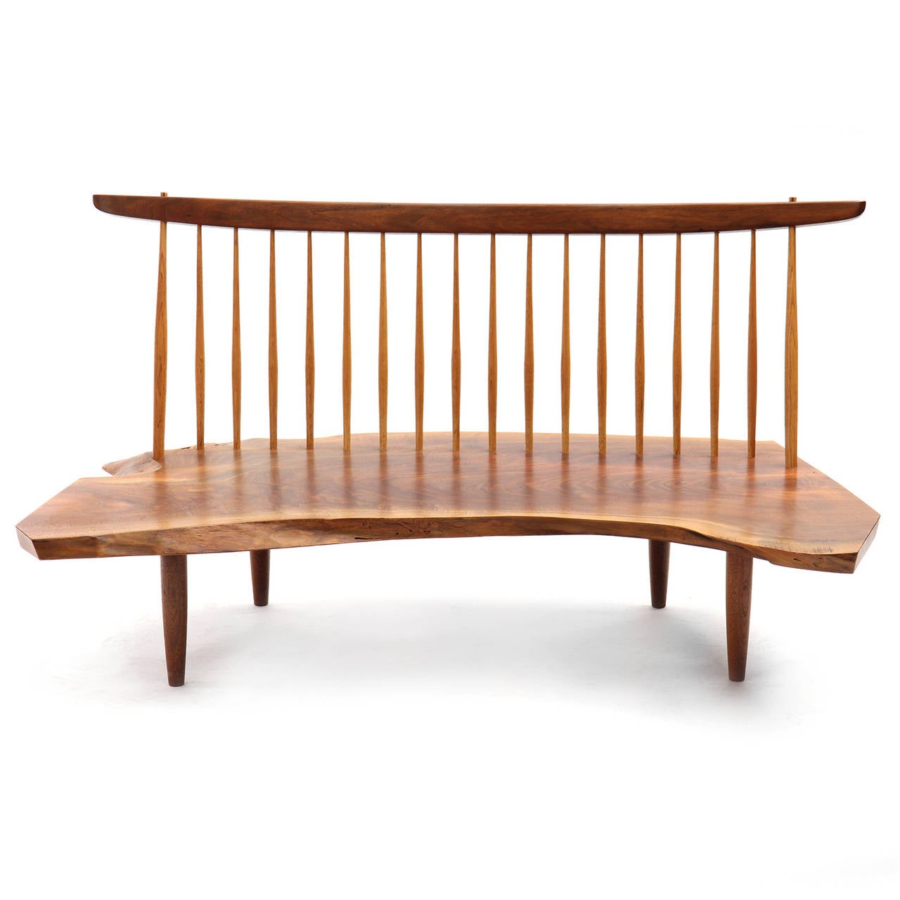 An impeccable studio-made Conoid bench having a highly expressive free edged single slab black walnut seat with hand hewn hickory spindles supporting  a sculpted walnut top rail, the seat element floating atop dowel form turned legs.

.