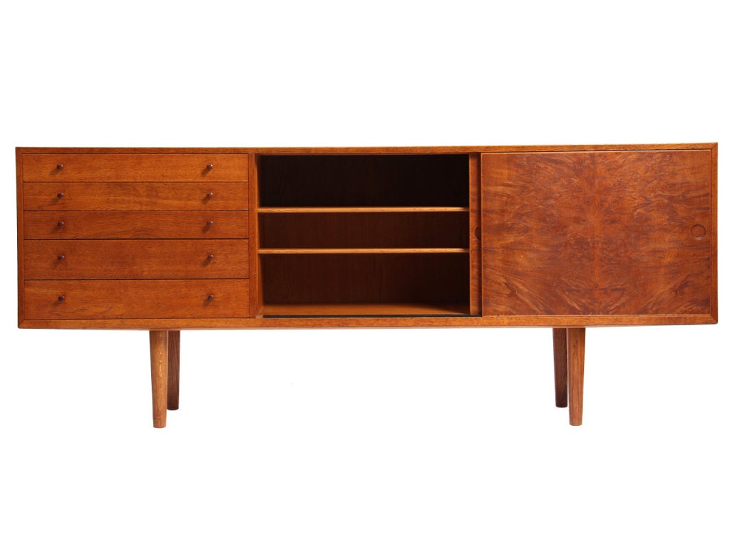 A rare oak and burled oak door server / sideboard / credenza designed by Hans Wegner. The cabinet features three sections, one five-drawer unit, and two shelved units with sliding doors and adjustable trays. Crafted by cabinetmaker Johannes Hansenin