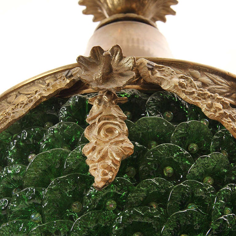 A neoclassical acorn form ceiling fixture composed of bronze and scalloped green glass.