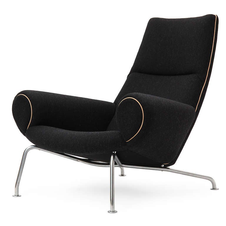 A sculptural and generous lounge chair having a modeled seat, floating on dramatically angled chromed steel legs. This highly comfortable chair has been impeccably reupholstered in a charcoal Savak wool with natural leather welting.