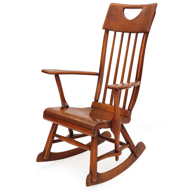 A masterful rocking chair in maple, having an Arts & Crafts influence and an array of expressive details. Carved paddle arms, molded seat, top rail cut-out and abundant through-tenon joinery.