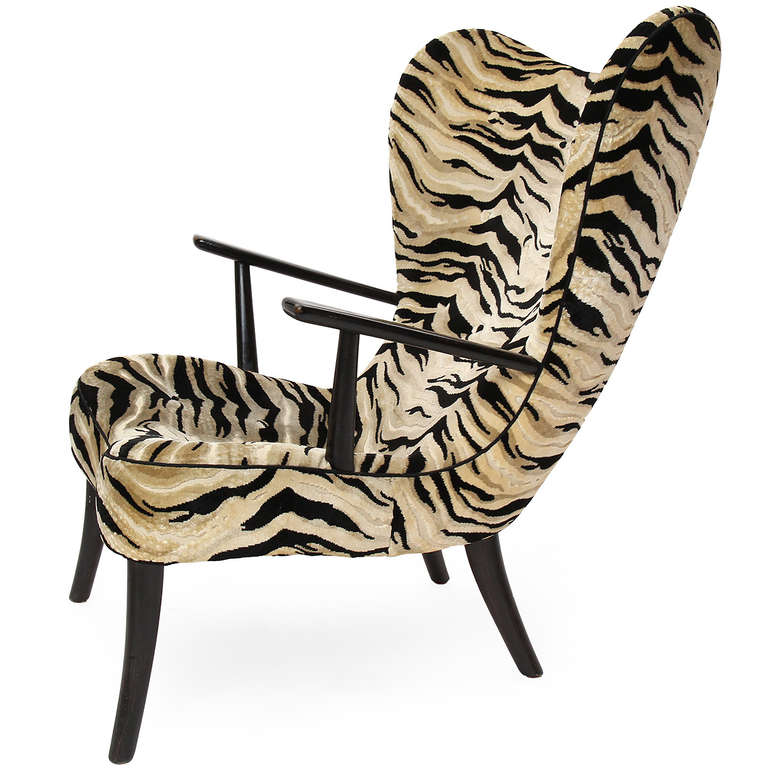 A well-scaled lounge chair and ottoman, having a curving seat upholstered in a zebra-patterned fabric with cantilevered flattened arms resting on splayed legs.