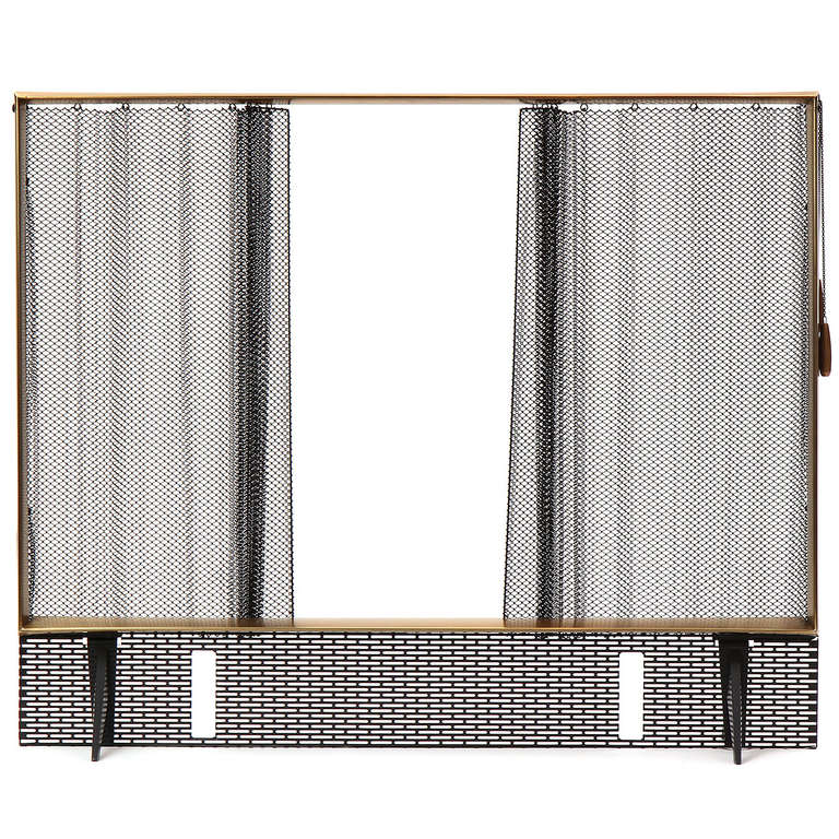 A footed fire screen having a brass beveled frame and a retractible steel mesh curtain opened by a chain with elegant brass pulls. The lower part of the screen with spark arrester and slotted to receive andirons.