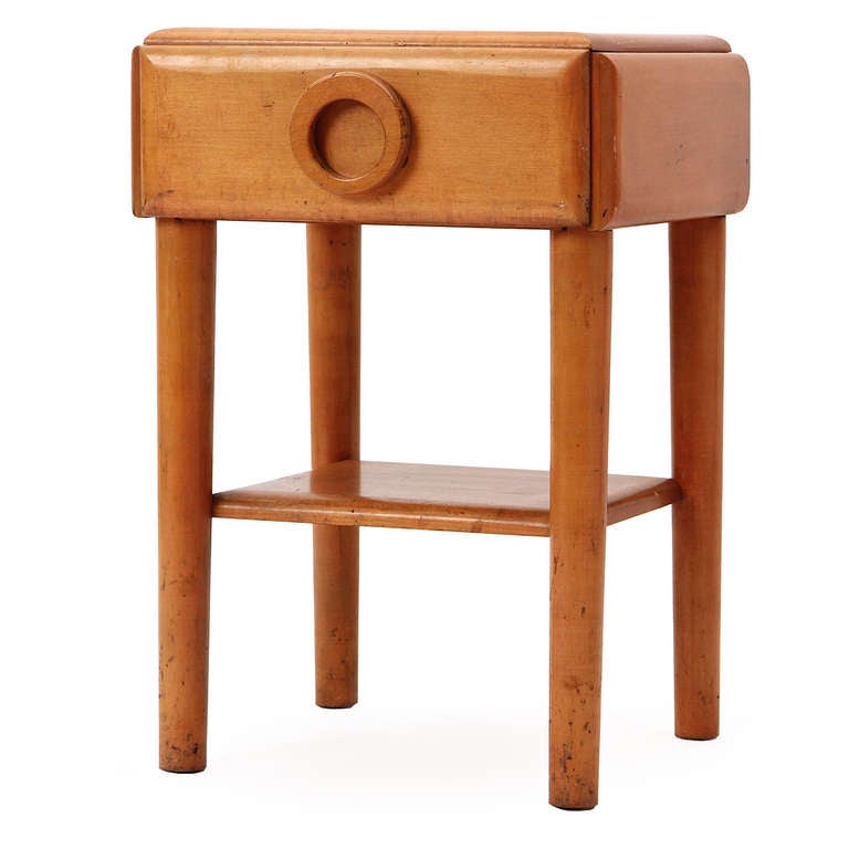 A simple and solidly constructed nightstand made of solid maple, having straight dowel legs, a lower shelf and a single drawer with an expressive round pull. From Russel Wright's seminal American modern furniture line.