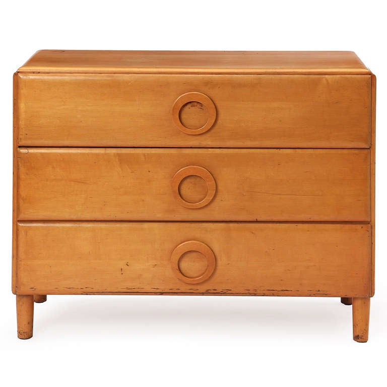 A simple and well-constructed uncommon chest of drawers made of solid maple, having straight dowel legs and three drawers with expressive circular pulls.