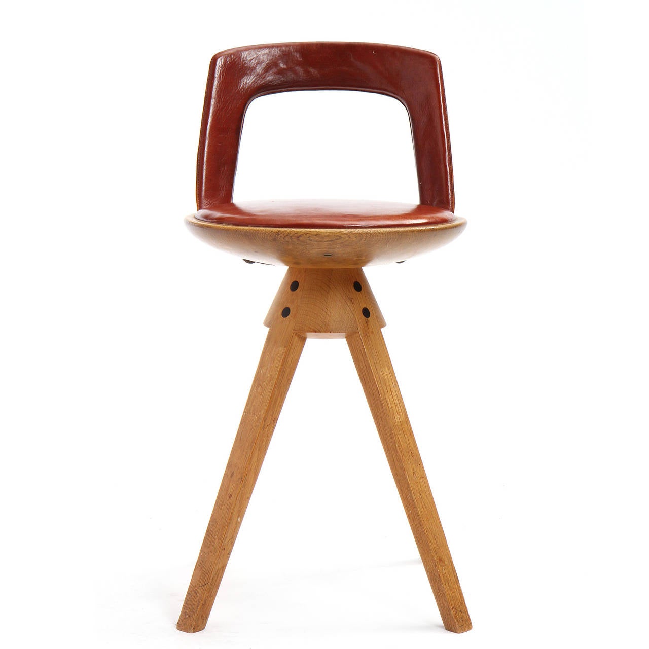 A rare swivel seat stool with a low leather backrest and seat cushion, on splayed oak tapered legs.