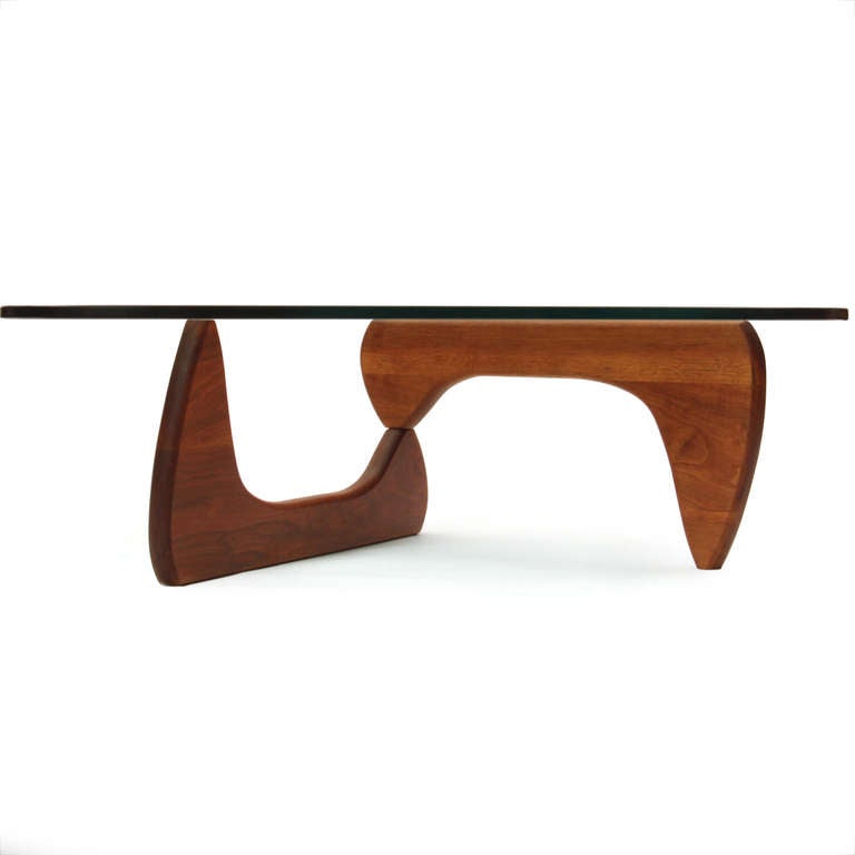 An early Noguchi low table (IN-50) with original glass top resting on interconnected pivoting walnut supports.