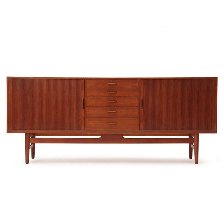A long teak credenza/ cabinet/ sideboard with two storage sections concealed by tambour doors flanking five central drawers. Each drawer handle has a wenge inlay.