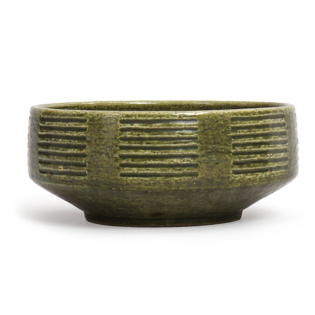 A beautiful and well-scaled footed unique stoneware bowl having horizontal parallel stacks of incised decoration and covered in a lustrous and variegated deep green glaze.