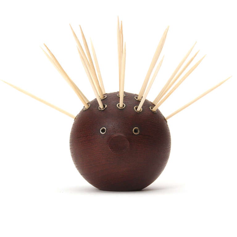 A blowfish-shaped toothpick holder in solid teak with nickel eyelets.