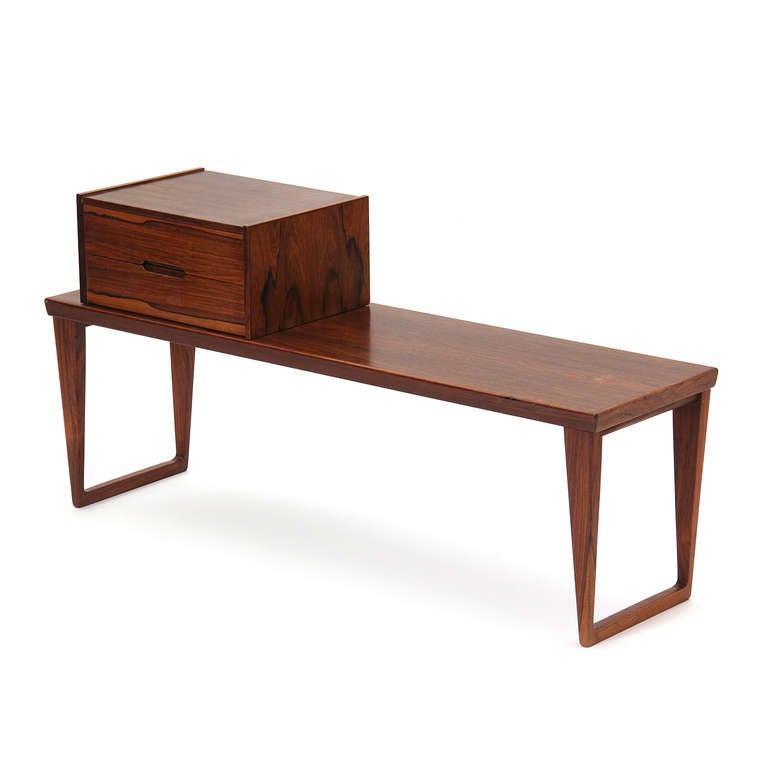 A highly figured minimalist rosewood bench or coffee table with sled legs with an accompanying two-drawer cabinet having recessed pulls. Box is 16
