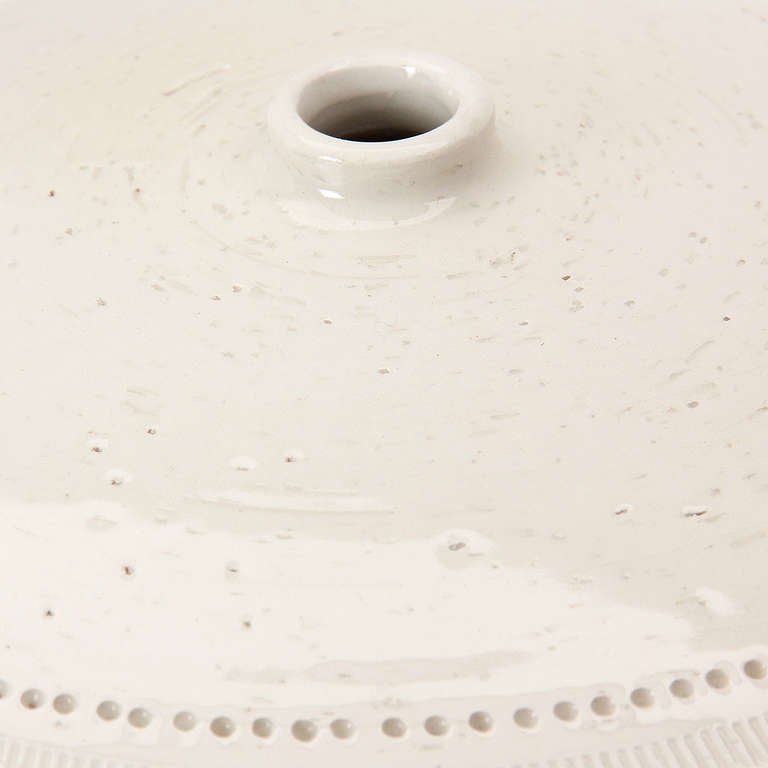 A large ceramic vase of bulbous form in a matte cream glaze with rhythmic embossed decoration.