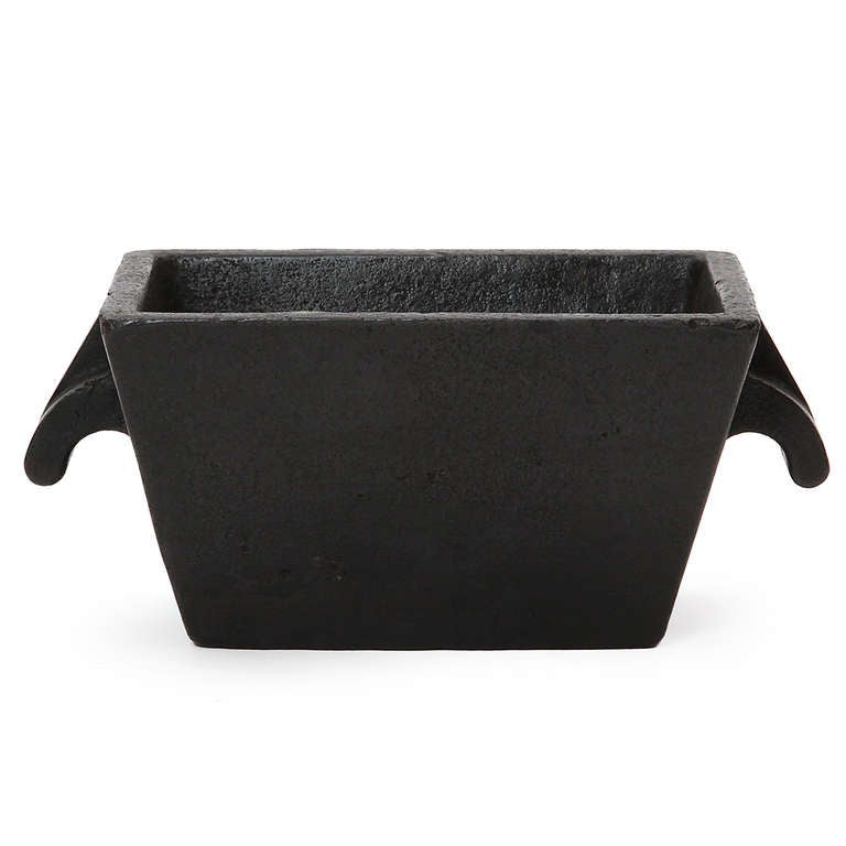 A tall, steep-walled and finely rendered cast iron industrial planter of rectangular tapering form with sculptural handles.