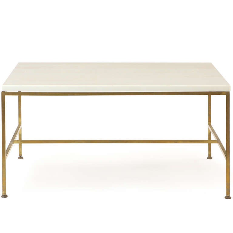 A masterfully minimal rectilinear coffee or occasional table made of square-gauge brass tubing that supports a milk glass top.