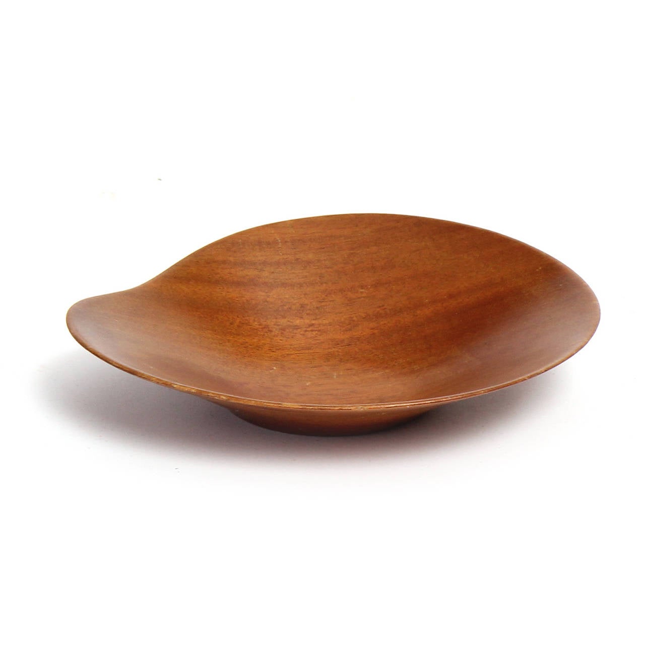 A finely turned thin-walled bowl in mahogany having a flattened oblong organic form with an undulating rim.
