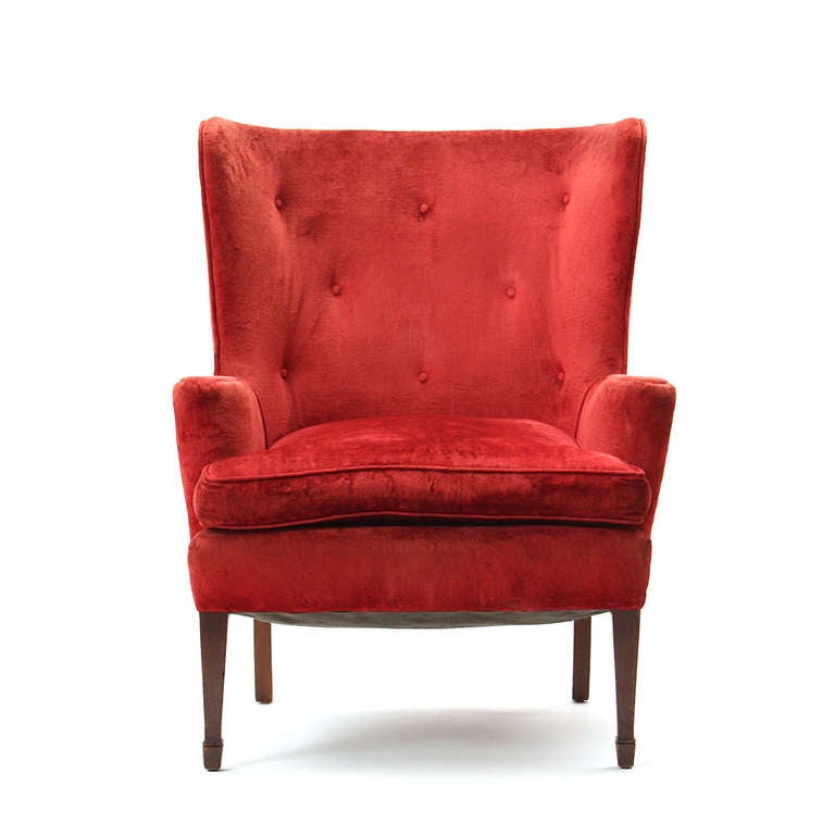 A pair of sculptural wingback chairs with mahogany legs retaining the original crushed red velvet upholstery.