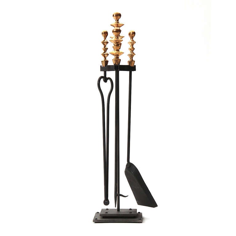 A finely crafted andiron set in gilt-bronze and iron after a design by Diego Giacometti.

Tools measure 8
