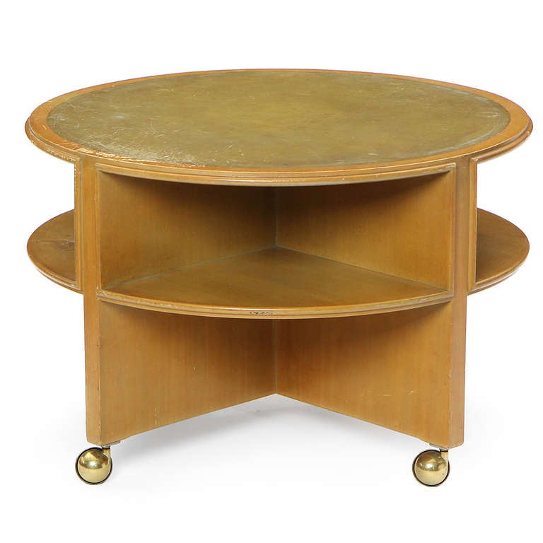 An interesting and uncommon occasional table on casters having a cruciform structure intersected by two circular planes, the top of the table surfaced with leather.
